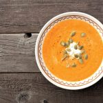 Creamy butternut squash soup, above view on a rustic wood backgr